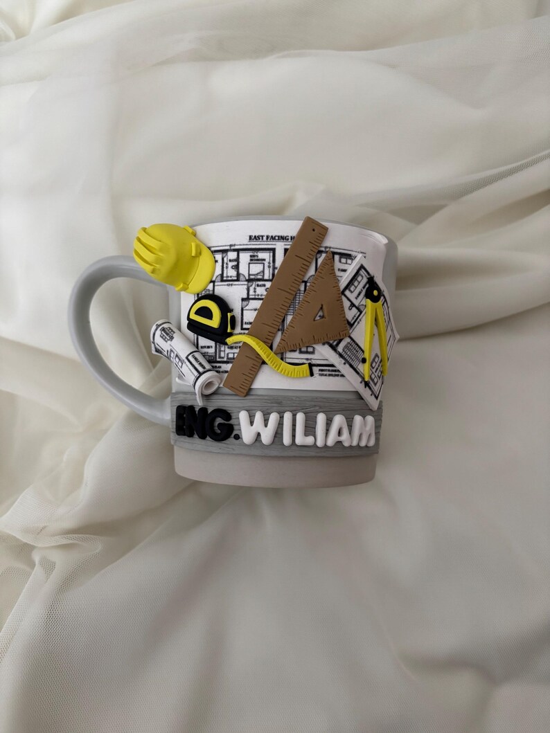 Puede incluir: Una taza de cer&aacute;mica gris claro con un dise&ntilde;o decorativo en 3D de herramientas de ingenier&iacute;a, incluyendo un casco amarillo, una cinta m&eacute;trica, una regla, una escuadra y un comp&aacute;s sobre un plano. El nombre ENG. WILIAM est&aacute; en relieve blanco.