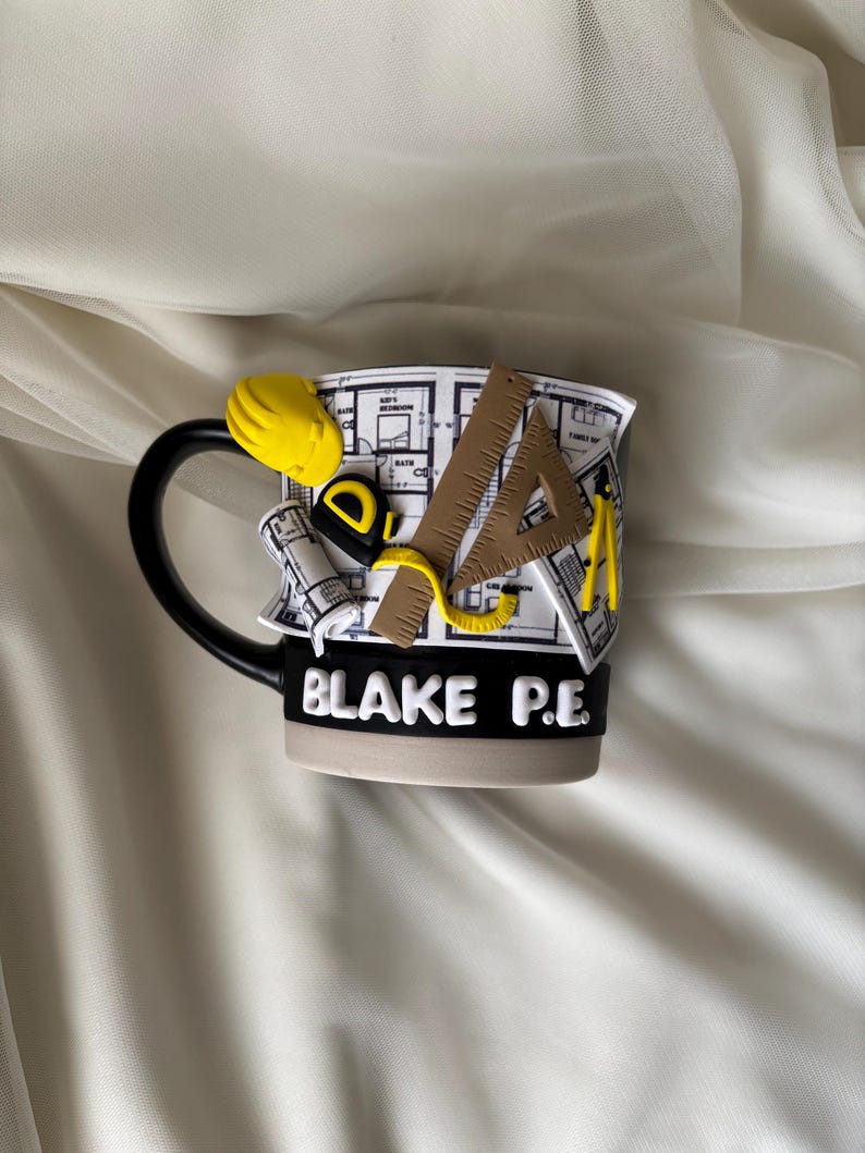 Puede incluir: Una taza de cer&aacute;mica en blanco y negro con un dise&ntilde;o arquitect&oacute;nico en 3D que incluye un casco amarillo, una cinta m&eacute;trica, una regla triangular y un comp&aacute;s. La taza muestra un patr&oacute;n de plano y el texto blanco BLAKE P.E. en una banda negra.