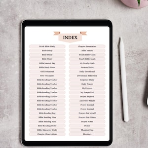 May include: A digital tablet displaying an index of Bible study topics. The screen shows a list of categories such as "SOAP Bible Study," "Bible Verses," and "Daily Prayer." A white stylus rests beside the tablet on a light gray surface. A small potted plant is in the background.
