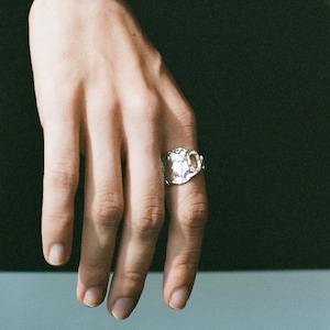 Peut inclure: Une bague en argent avec une forme de surface irrégulière, organique et texturée. La bague présente un design en métal fondu proéminent qui s'enroule autour du doigt, affichant une finition réfléchissante et inégale avec une petite ouverture.