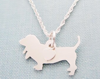 May include: A silver necklace with a dachshund silhouette pendant and a small heart charm. The chain is a delicate rope style.