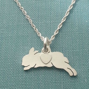 May include: A silver necklace with a delicate chain and a pendant shaped like a jumping rabbit with a small heart charm.