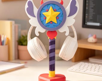 May include: A whimsical headphone stand featuring a star and wing design with a red heart base. The stand has a purple and yellow star emblem, white wings, and holds white headphones. The stand is approximately 10 inches tall.