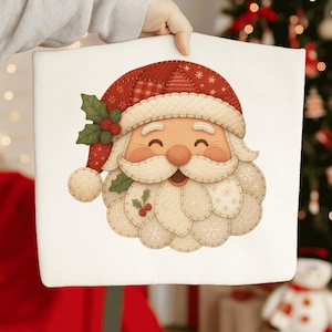 Op de afbeelding: Een wit kussen met een lachend gezicht van de kerstman. Het gezicht van de kerstman heeft een rood-witte hoed, een witte baard en een roze gezicht. Het kussen wordt door een persoon vastgehouden.