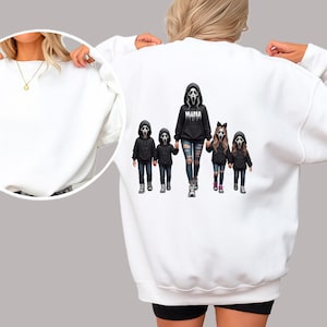May include: A white long-sleeve sweatshirt featuring a graphic on the back of a group of five figures wearing black hoodies and white ghost masks. The central figure wears a hoodie with the word MAMA printed on the front in white text.