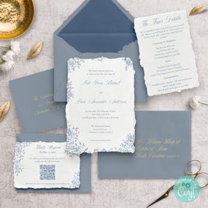 May include: A wedding invitation suite featuring a main invitation, RSVP card, and details card. The stationery has a textured, off-white paper with blue floral accents and matching blue envelopes. Gold text and a QR code are also visible.