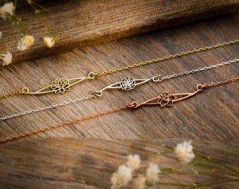 Puede incluir: Tres delicados collares de oro, plata y oro rosa con un colgante de diseño floral. Cada collar presenta un acabado metálico diferente.