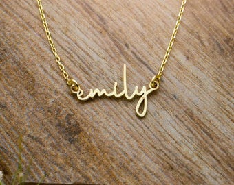 May include: A gold-toned necklace featuring a delicate chain and a central nameplate pendant displaying the name emily in a cursive script font. The metal has a polished finish and the pendant is securely attached to the chain on both sides.