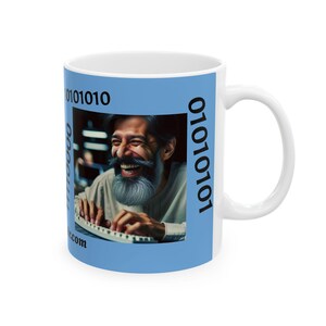 May include: White ceramic mug with a light blue background. The mug features a photo of a man laughing while typing on a keyboard. The text "01010101" is on the right side of the mug and the text "0101010" is on the left side of the mug.