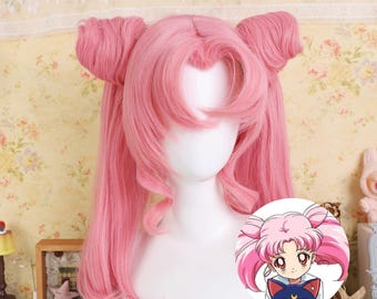 May include: A pink wig styled with two high pigtails and long, flowing hair. The wig is displayed on a white mannequin head. A small, circular graphic shows a cartoon character with a similar hairstyle.