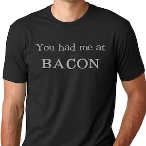 May include: A black t-shirt with the text "You had me at BACON" printed in gray.