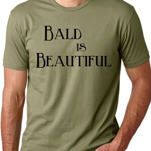 May include: A green t-shirt with the text "BALD IS BEAUTIFUL" printed in black.