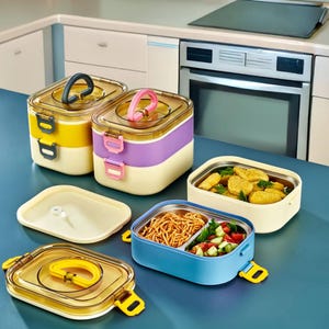 May include: A collection of rectangular lunch containers with translucent lids and carrying handles. Two stacked containers are yellow and purple, while two open containers reveal compartments filled with noodles, salad, and breaded chicken pieces.