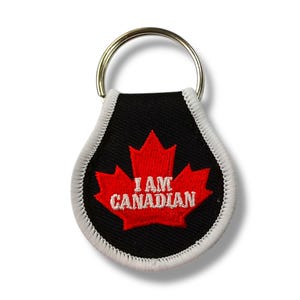 May include: A black and white key chain with a red maple leaf and the text "I AM CANADIAN".