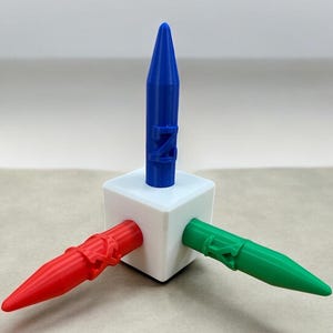 May include: A white cube with three coloured, pointed projections: red, green, and blue. The blue projection is vertical, while the red and green ones extend horizontally. The blue projection has the letter "Z" on it.