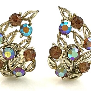 May include: A pair of silver tone clip-on earrings with a leaf design and iridescent and brown rhinestones.