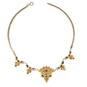May include: A gold chain necklace with a cluster of small, clear and amber-colored stones in the center and smaller clusters of stones dangling from the sides.