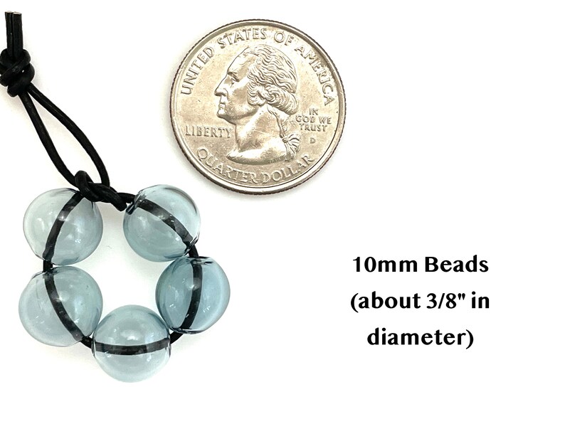 May include: A strand of six light blue glass beads with a black stripe around each bead. The beads are strung on a black elastic cord. A US quarter is shown for size comparison. 10mm Beads (about 3/8" in diameter)
