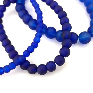 May include: Three blue beaded bracelets made of frosted glass beads.