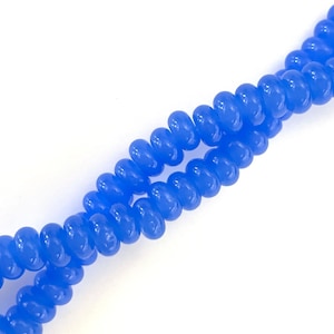 May include: A strand of light blue glass beads, each bead is shaped like a small, rounded cylinder.