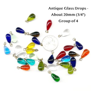 May include: A collection of antique glass drops in various colors, including blue, red, green, yellow, and clear. Each drop is approximately 20mm (3/4") in size and has a small metal loop for hanging. The text in the image reads "Antique Glass Drops - About 20mm (3/4") Group of 4."