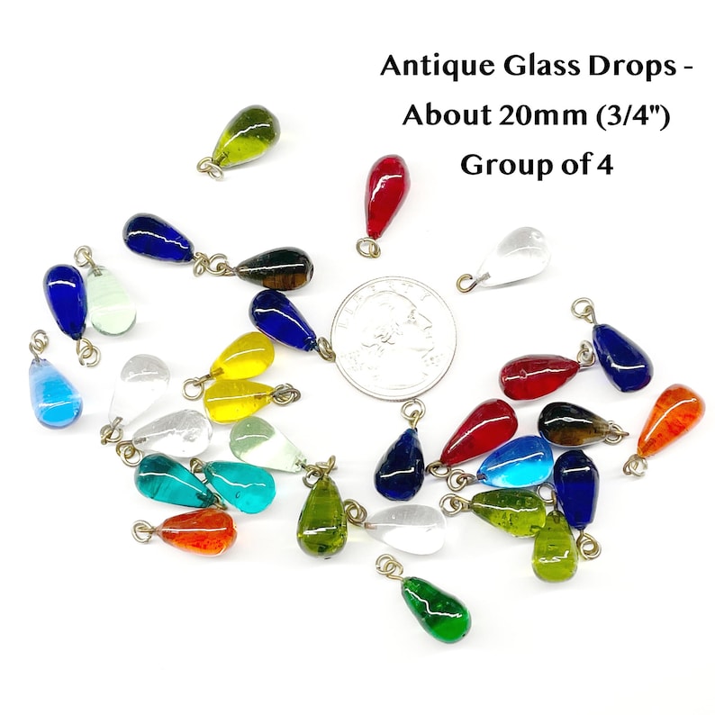 May include: A collection of antique glass drops in various colors, including blue, red, green, yellow, and clear. Each drop is approximately 20mm (3/4") in size and has a small metal loop for hanging. The text in the image reads "Antique Glass Drops - About 20mm (3/4") Group of 4."