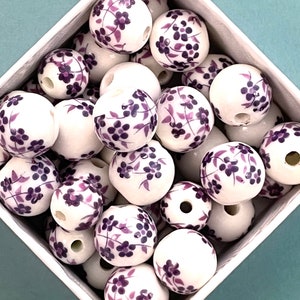 Loose round ceramic porcelain beads are piled loose within a diamond shape container that sits on a pale blue surface