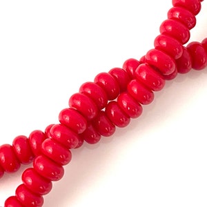 May include: A strand of bright red, glossy, round beads. The beads are strung together in a continuous loop.