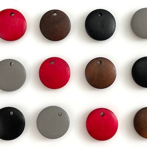 May include: Twelve round wooden discs in various colors, including red, brown, black, and gray. Each disc has a small hole in the center.