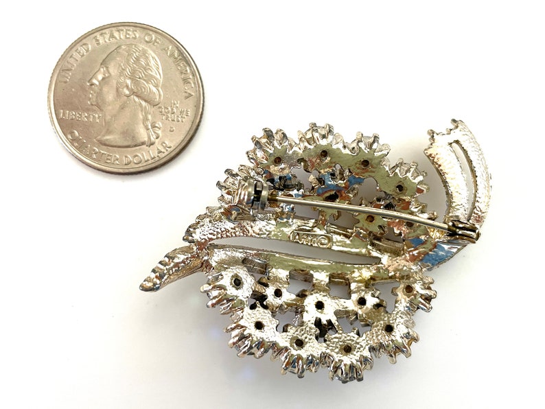 May include: Silver tone brooch with a leaf design and rhinestones. The brooch has a pin back and is marked "Coro".