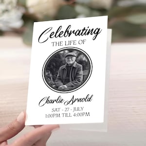 May include: A white memorial card held by a hand. The card features the text "Celebrating THE LIFE OF" above a black and white photo of a man. Below the photo is the name "Charlie Arnold" and event details.