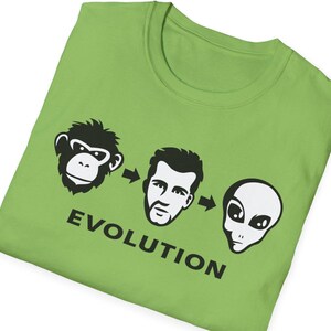 May include: A green t-shirt with a black graphic of a monkey, a man, and an alien with arrows pointing from the monkey to the man and from the man to the alien. The text "EVOLUTION" is printed below the graphic.