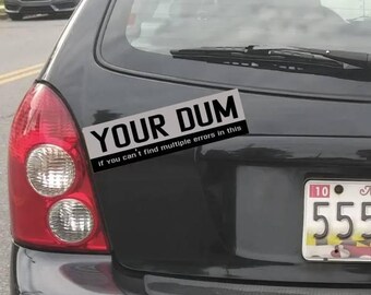 May include: A black car with a bumper sticker that reads "YOUR DUM If you can't find multiple errors in this".