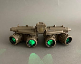 May include: Tan night vision goggles with six green lenses. The goggles have a central housing and adjustable features. The text "A.R.K SMITH" is printed at the bottom of the image.
