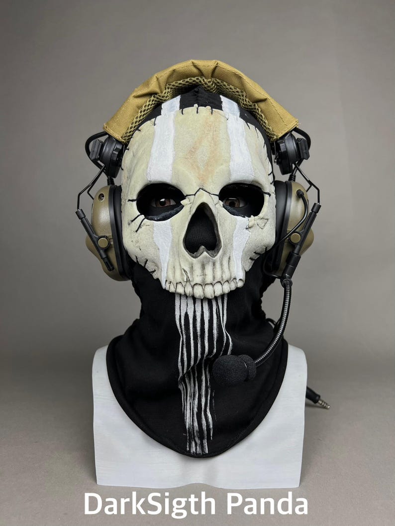 May include: A skull mask with a black hood and white vertical stripes. The mask has a beige and white color scheme with black eye sockets and a black nose. The mask is adorned with a headset and a microphone. The text "DarkSigth Panda" is at the bottom.