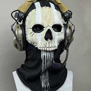 May include: A skull mask with a black balaclava and a tan headset. The mask has white stripes and a black nose and eye sockets. The headset has a microphone and is olive green. The text "DarkSigth Panda" is at the bottom.