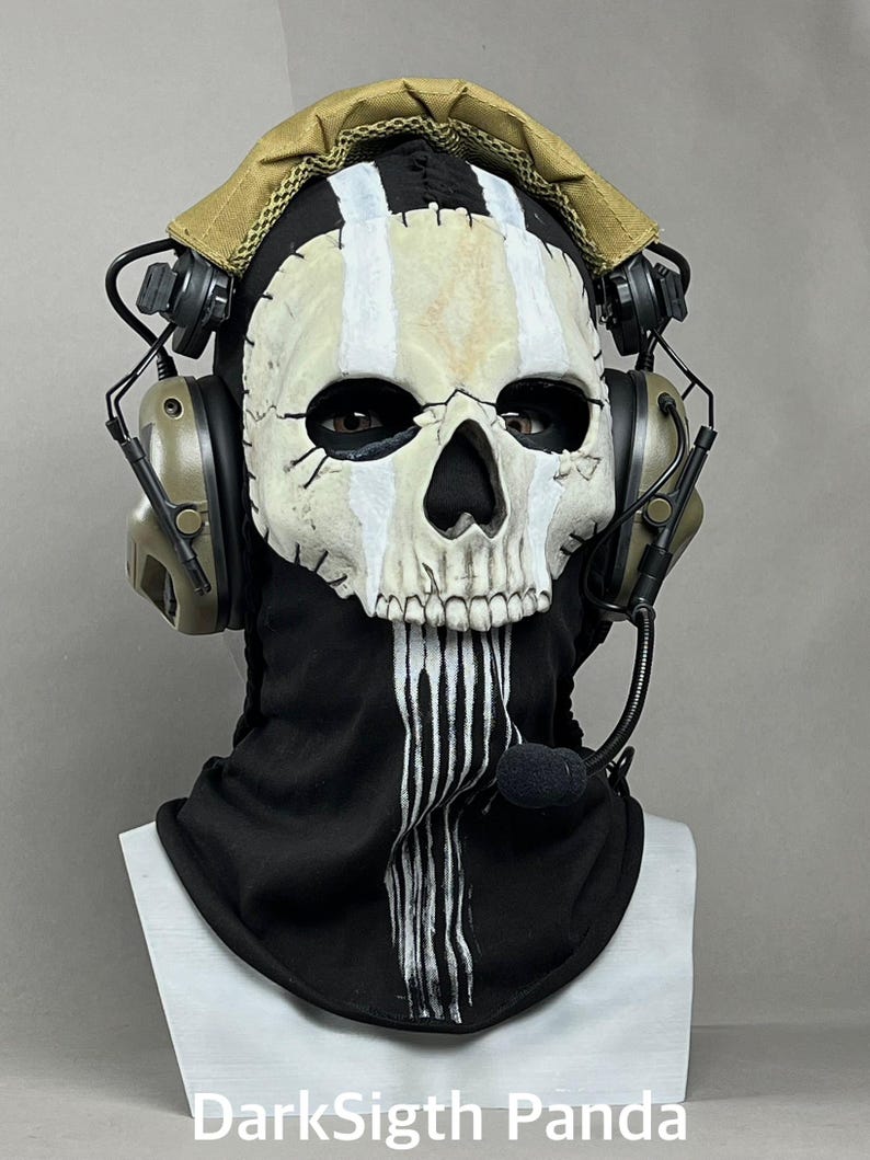 May include: A skull mask with a black balaclava and a tan headset. The mask has white stripes and a black nose and eye sockets. The headset has a microphone and is olive green. The text "DarkSigth Panda" is at the bottom.