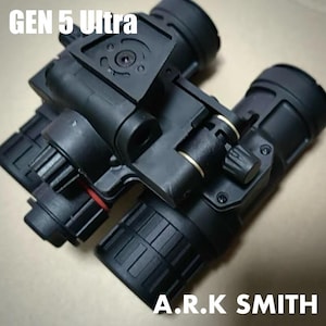 May include: Black night vision device with the text "GEN 5 Ultra" and "A.R.K SMITH". The device has multiple lenses and adjustable dials. The device is made of black plastic and has a complex design.