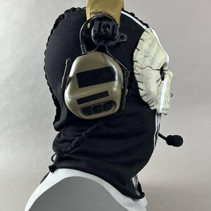 May include: A black balaclava with a white skull mask and attached headset. The balaclava has white stripes and a drawstring. The headset is tan and black. The text "DarkSigth Panda" is at the bottom.