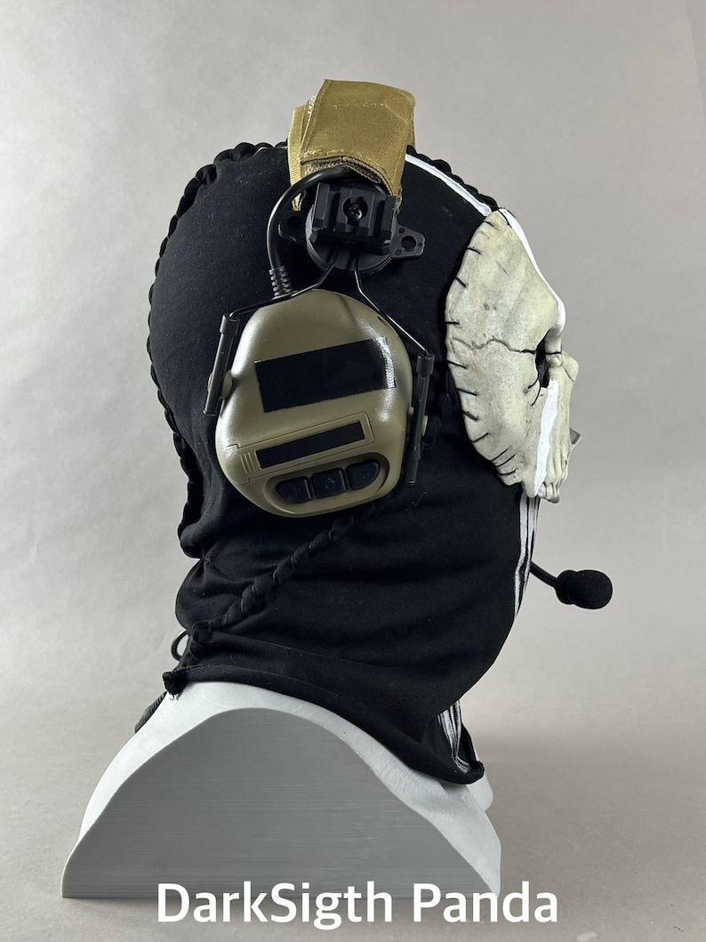 May include: A black balaclava with a white skull mask and attached headset. The balaclava has white stripes and a drawstring. The headset is tan and black. The text "DarkSigth Panda" is at the bottom.