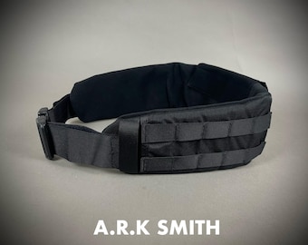 May include: Black tactical belt with a padded interior and MOLLE webbing. The belt features a quick-release buckle and is designed for attaching pouches and accessories. The text "A.R.K SMITH" is displayed at the bottom.
