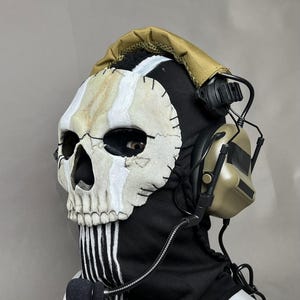May include: A black balaclava with a skull mask, white stripes, and a tan headset. The skull mask has a stitched design with white and tan accents. The headset has a microphone attached. The text "DarkSigth Panda" is visible.
