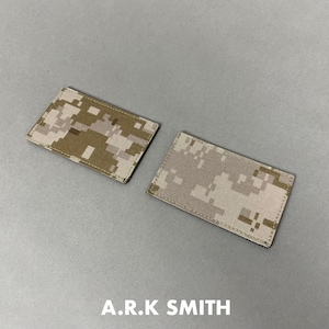 Może przedstawiać: Dwie prostokątne naszywki z cyfrowym wzorem kamuflażu w odcieniach beżu, brązu i beżu. Naszywki umieszczone są na szarej powierzchni. Tekst "A.R.K SMITH" jest wydrukowany na dole obrazu na biało.