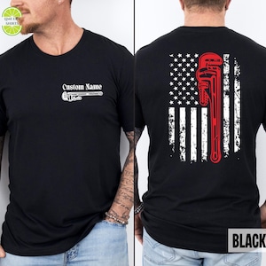 May include: Black t-shirt with a white wrench graphic and the text "Custom Name" on the front. The back features a distressed American flag design with a red pipe wrench. The word "BLACK" is in a white box at the bottom.
