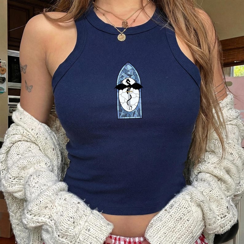 May include: Navy blue ribbed tank top featuring a dragon design within a stained glass window. The top has a round neck and is sleeveless. The dragon is black with a white background and blue detailing.