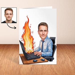 May include: A greeting card featuring a cartoon illustration of a man working on a laptop with flames erupting from it. The man is wearing a blue shirt and tie. A small photo of the man is in the upper left corner. The card is on a wooden surface.