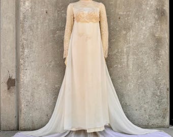 May include: A floor-length cream-colored gown featuring a high-neck lace bodice with long sleeves and a sheer overlay. The dress has a fitted empire waistline that transitions into a flowing, floor-length skirt with a long, circular train.