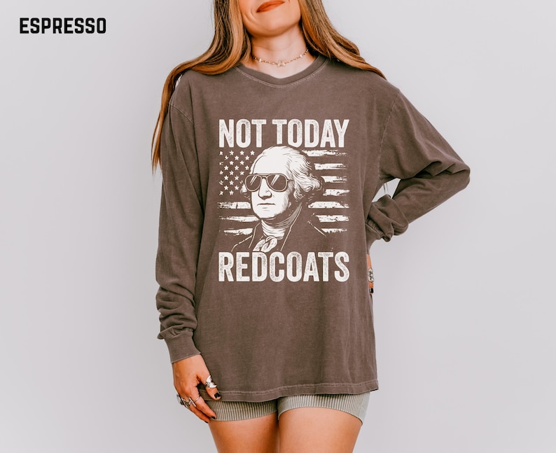 May include: Espresso-coloured long-sleeve shirt featuring a graphic of George Washington wearing sunglasses in front of an American flag. The text reads "NOT TODAY REDCOATS". The shirt has a vintage, worn appearance.