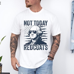 May include: White t-shirt featuring a navy blue graphic of George Washington in sunglasses, with the text "NOT TODAY REDCOATS". The design includes a navy blue American flag background.