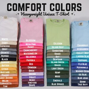 May include: Image of Comfort Colors heavyweight unisex t-shirts in various colors, including white, pink, green, and blue. Each color is labeled with its name, such as "Blossom," "Chambray," and "Emerald." The image showcases a wide range of options.